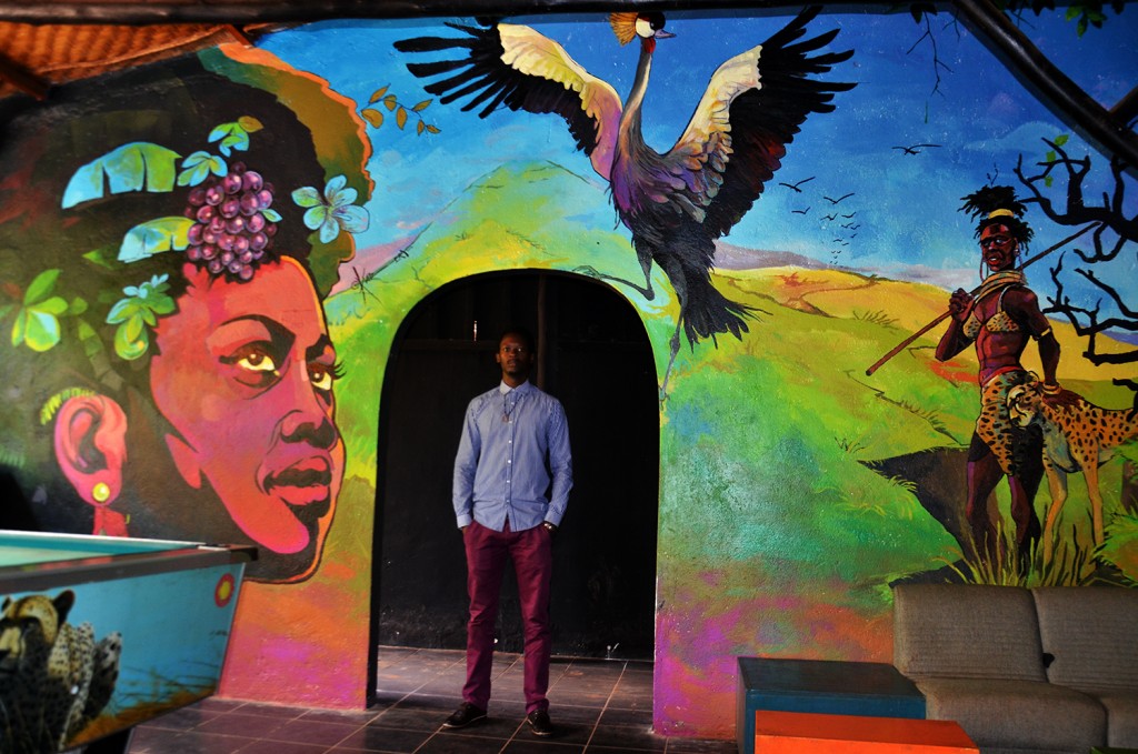 Kwizera stands in front of his mural painting at Iguana, where he also has his studio.